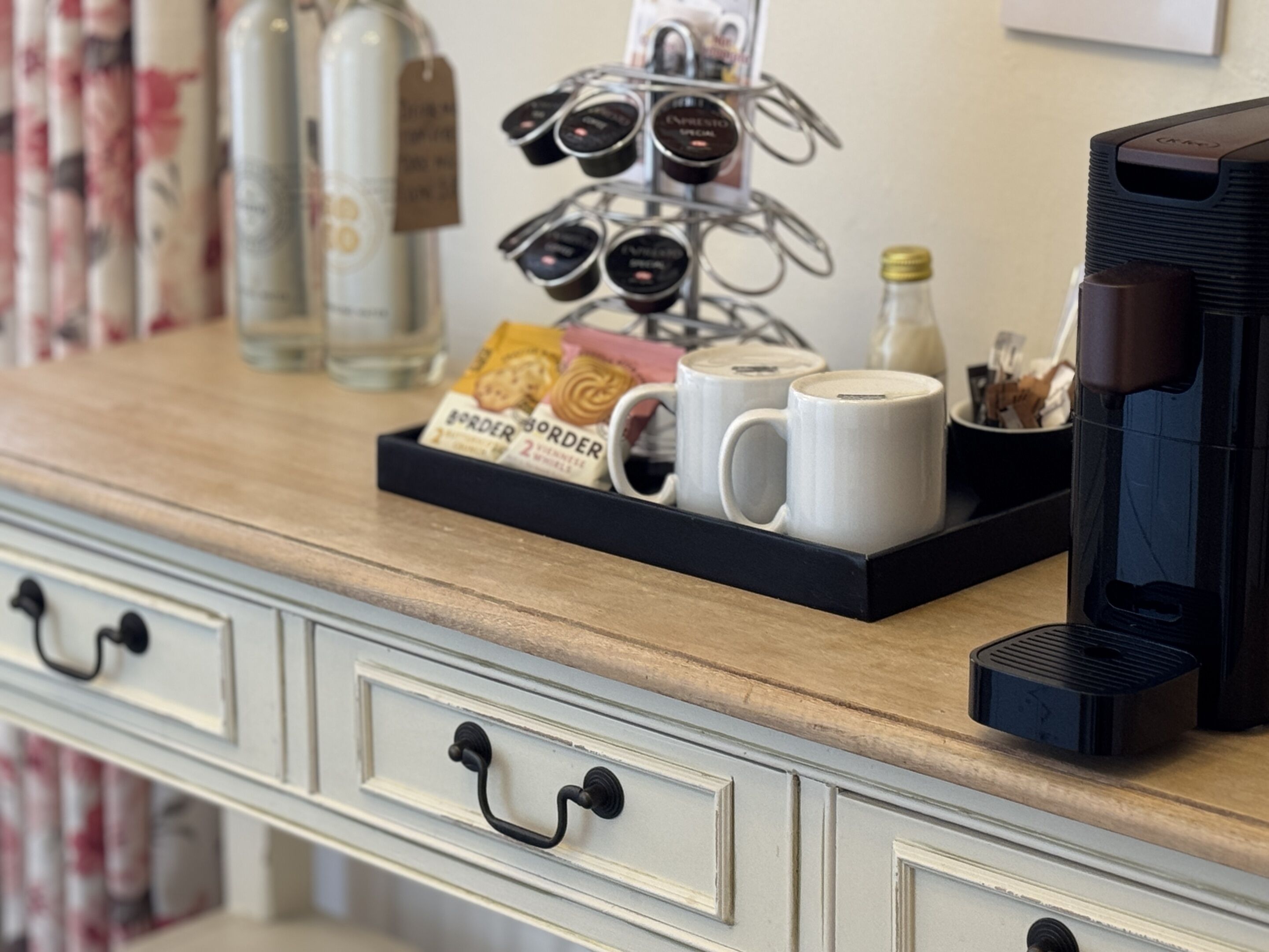 A coffee station with a tray of coffee cups, a coffee maker, and a bottle of water.