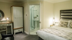 Een slaapkamer met een bed, een kledingkast, een bureau, een stoel, een nachtkastje, en een badkamer met een douche.