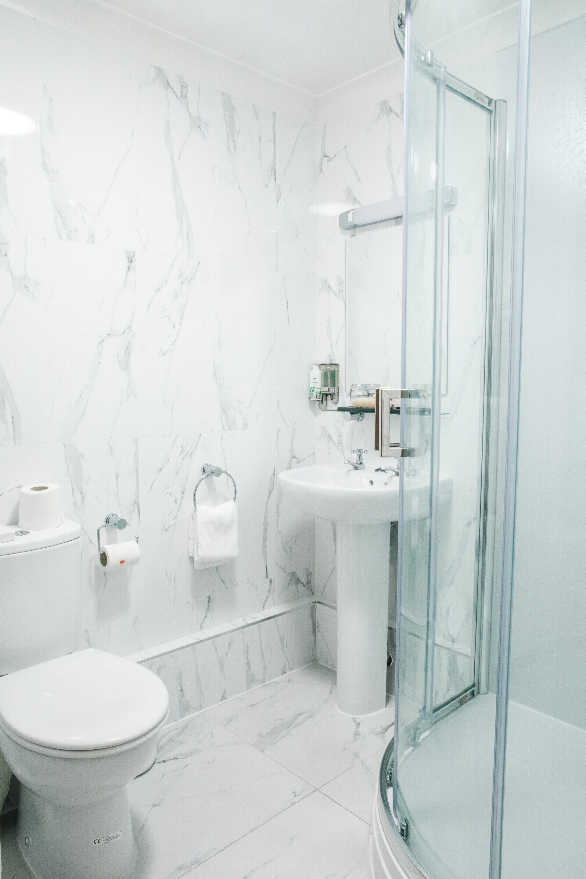 A bathroom with a toilet, sink, and glass shower enclosure.