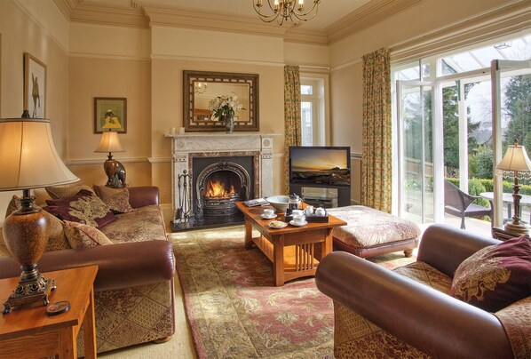 Un salón acogedor con chimenea, asientos cómodos y un ventanal con vistas al exterior.