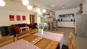 A modern living room with a dining area, a kitchen, and a hallway. - Beim Bicher (Grabenstätt)