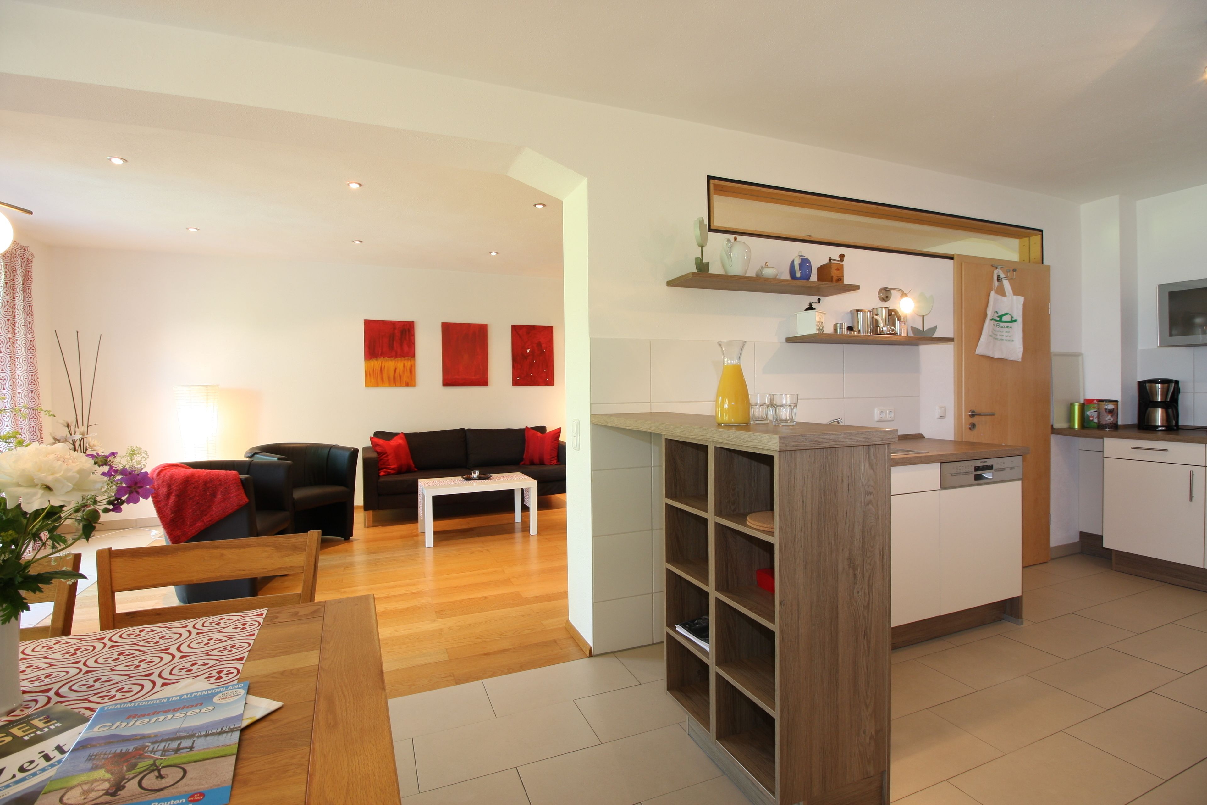 A modern kitchen with white cabinets, a wooden island, and a dining area with a table and chairs.