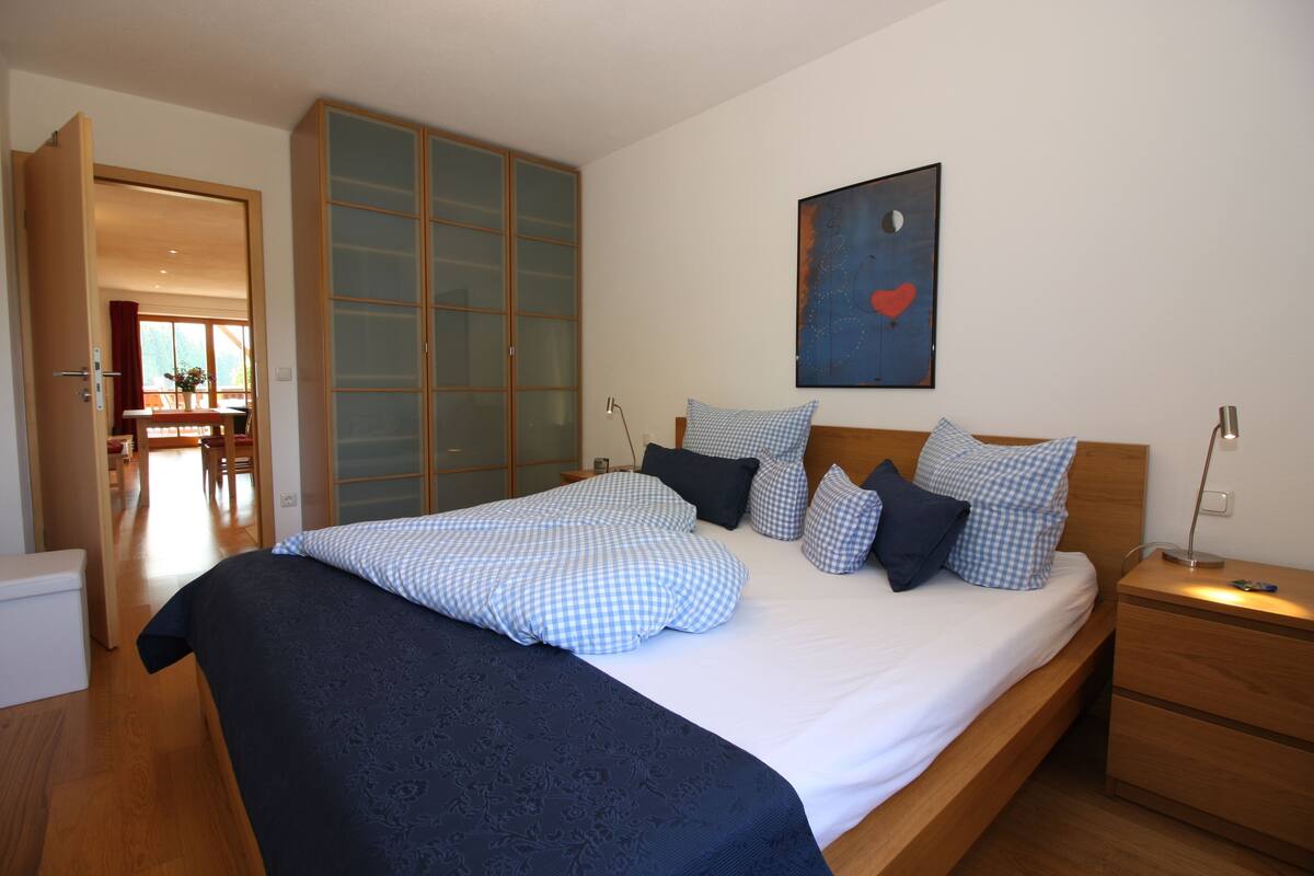 A bedroom with a bed, a nightstand, a wardrobe, and a painting on the wall.