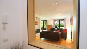 A modern living room with a large mirror reflecting the space, a sofa, a coffee table, and a television. - Beim Bicher (Grabenstätt)