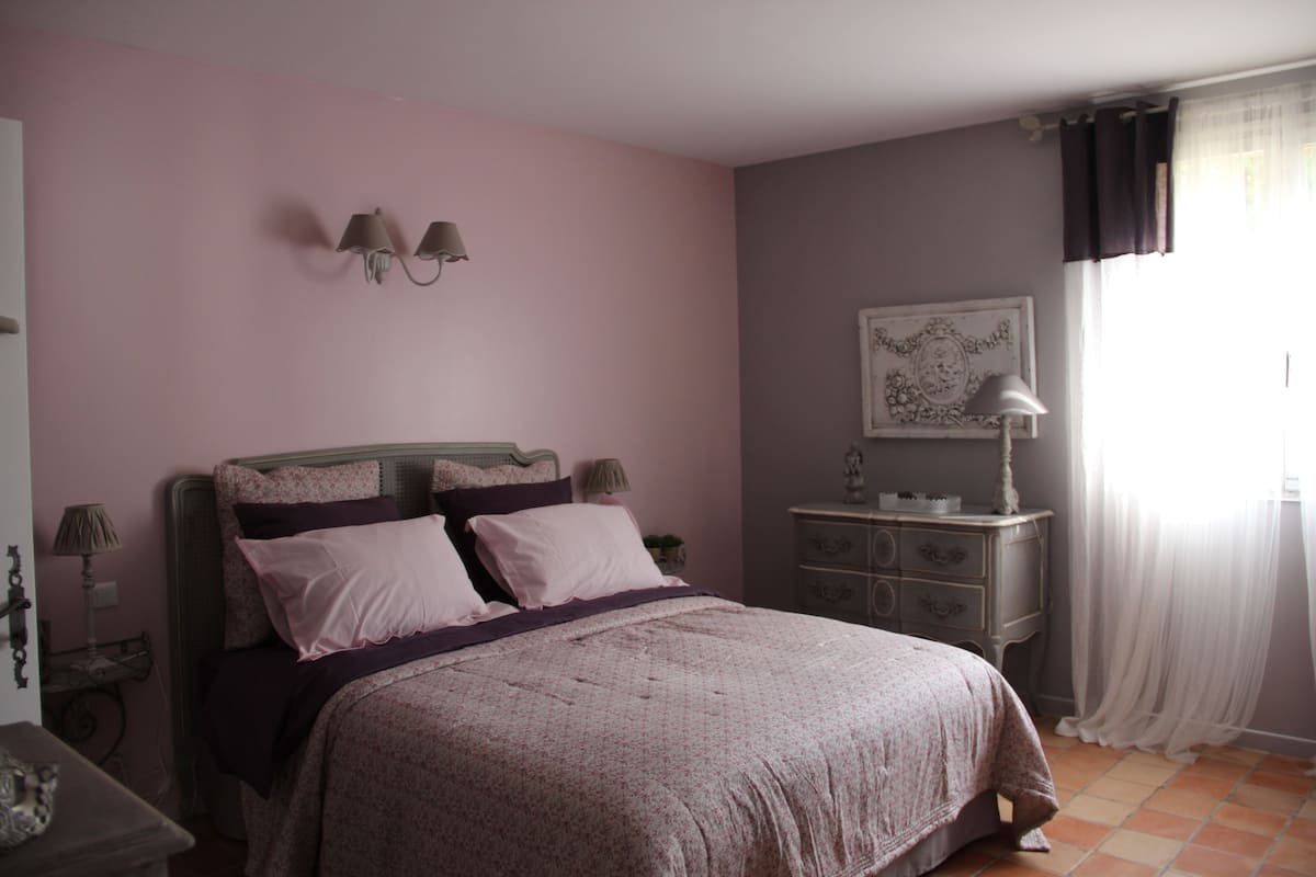 Une chambre à coucher avec un lit, une commode, une lampe et des éléments de décoration murale.