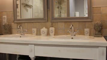 Une salle de bain avec un double lavabo, deux miroirs et un porte-serviettes.