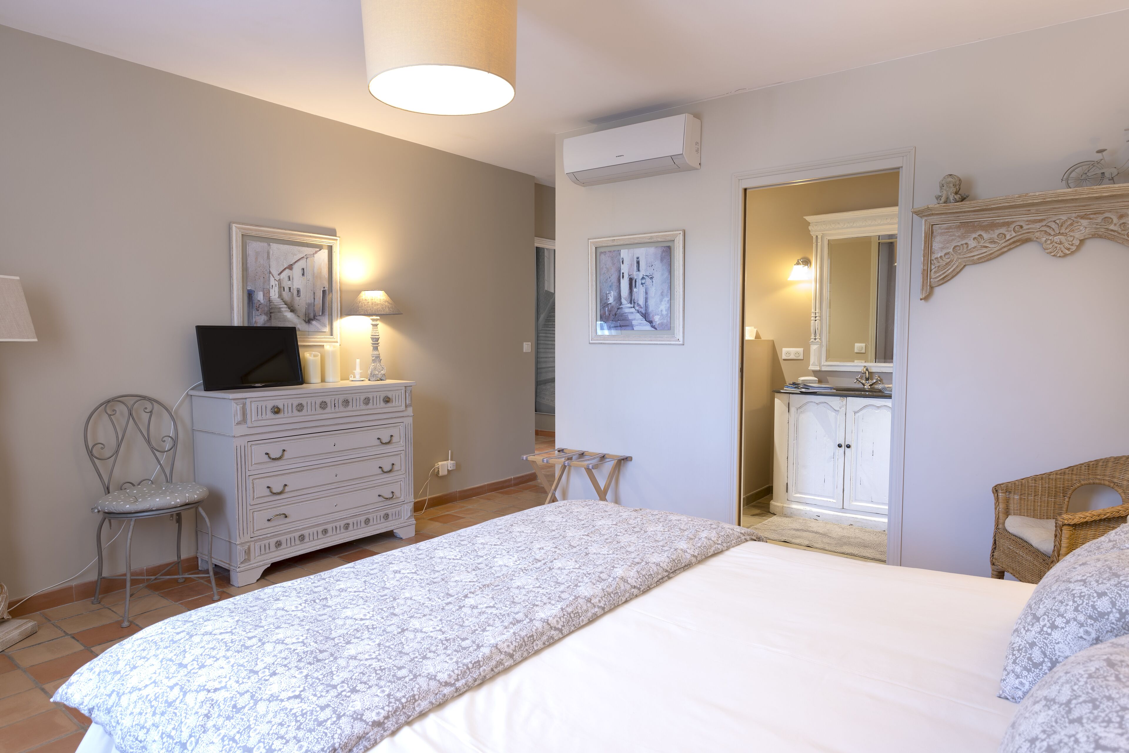 Un dormitorio con cama, cómoda, silla y obras de arte en las paredes.