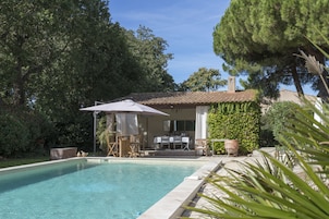 Une piscine avec un espace patio, du mobilier d’extérieur et un bâtiment doté d’un toit en tuiles.