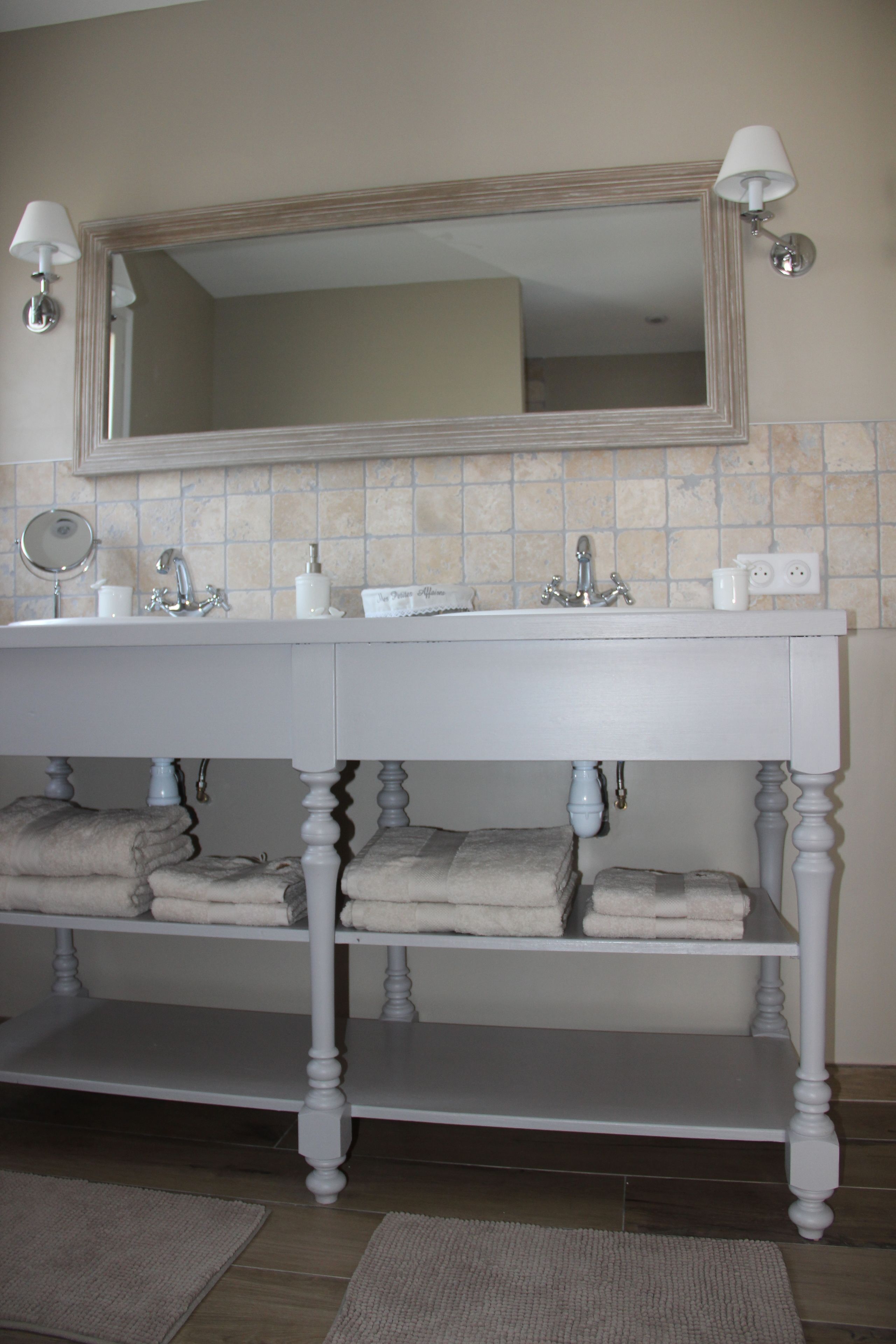 A bathroom with a white vanity, two sinks, a mirror, and a towel rack.