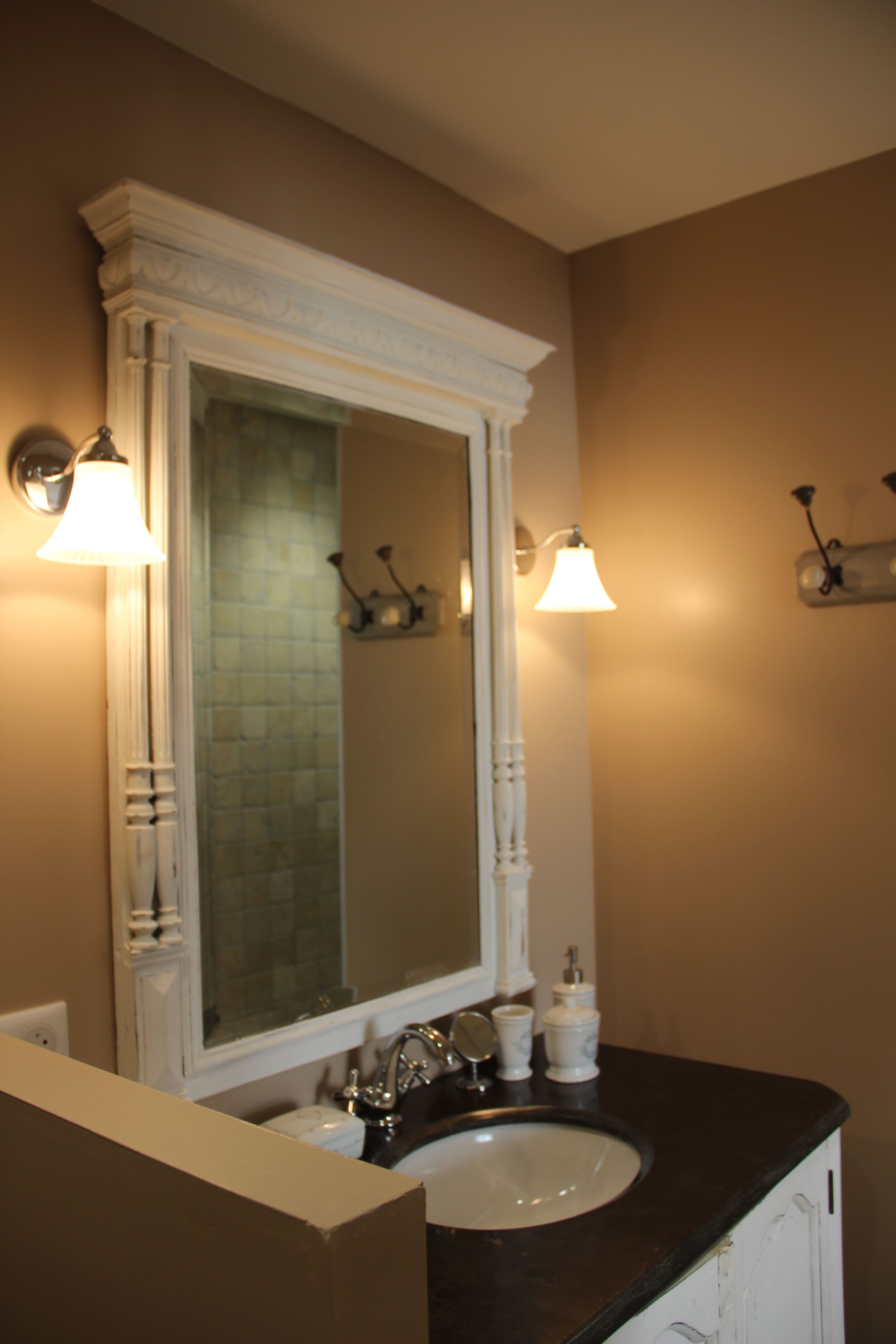 A bathroom with a white sink, a large mirror, and two wall-mounted lights.