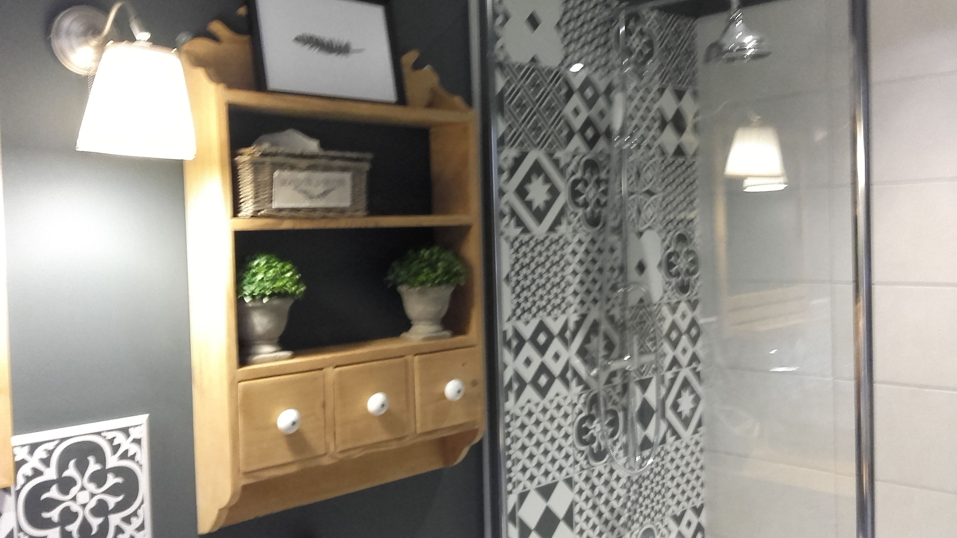 Un bany amb dutxa, una estantàcia decorativa i una paret amb motius.