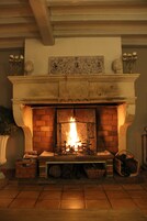 Une cheminée avec un feu, une étagère ornée d’objets décoratifs et un mur en briques.