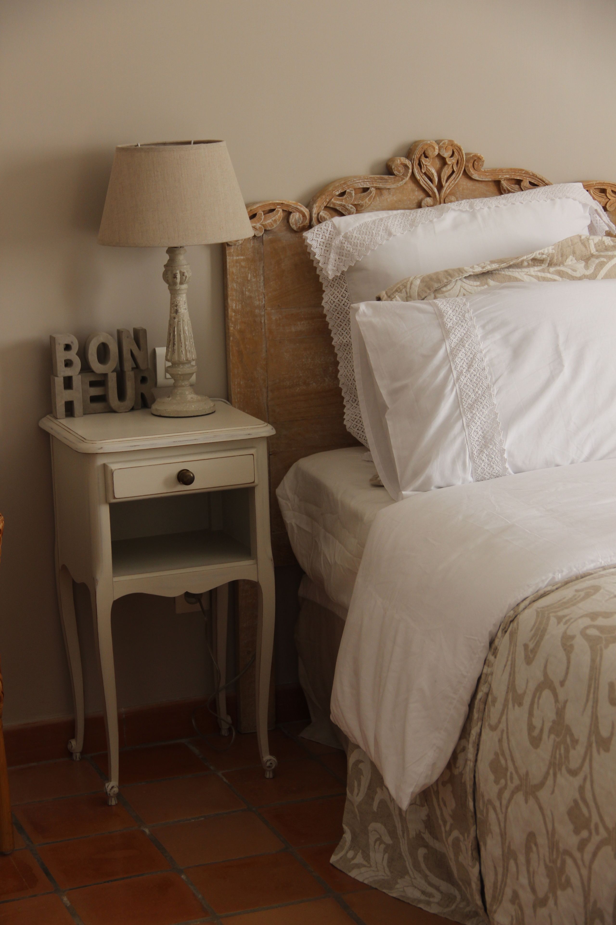 A bedroom with a bed, a nightstand with a lamp, and decorative pillows.