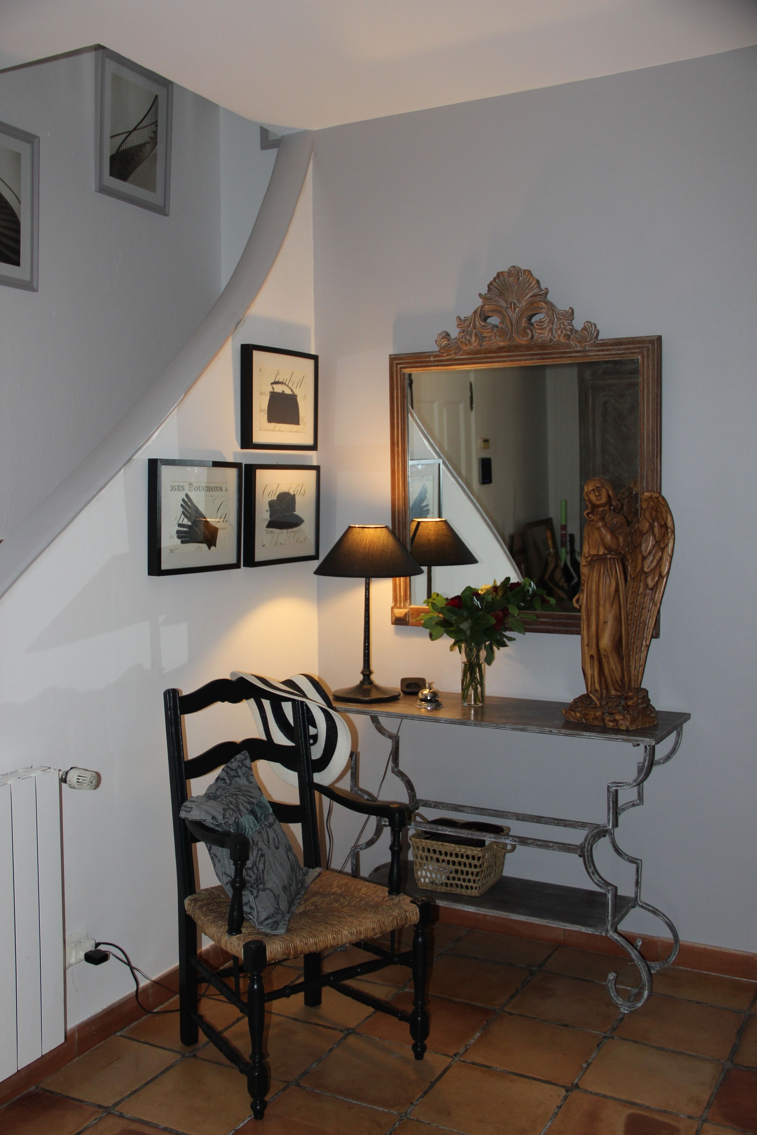 A staircase with a chair and a table with a lamp and a vase of flowers.