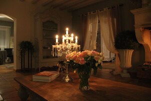 Une table en bois, sur laquelle se trouvent un vase de fleurs et une pile de livres.