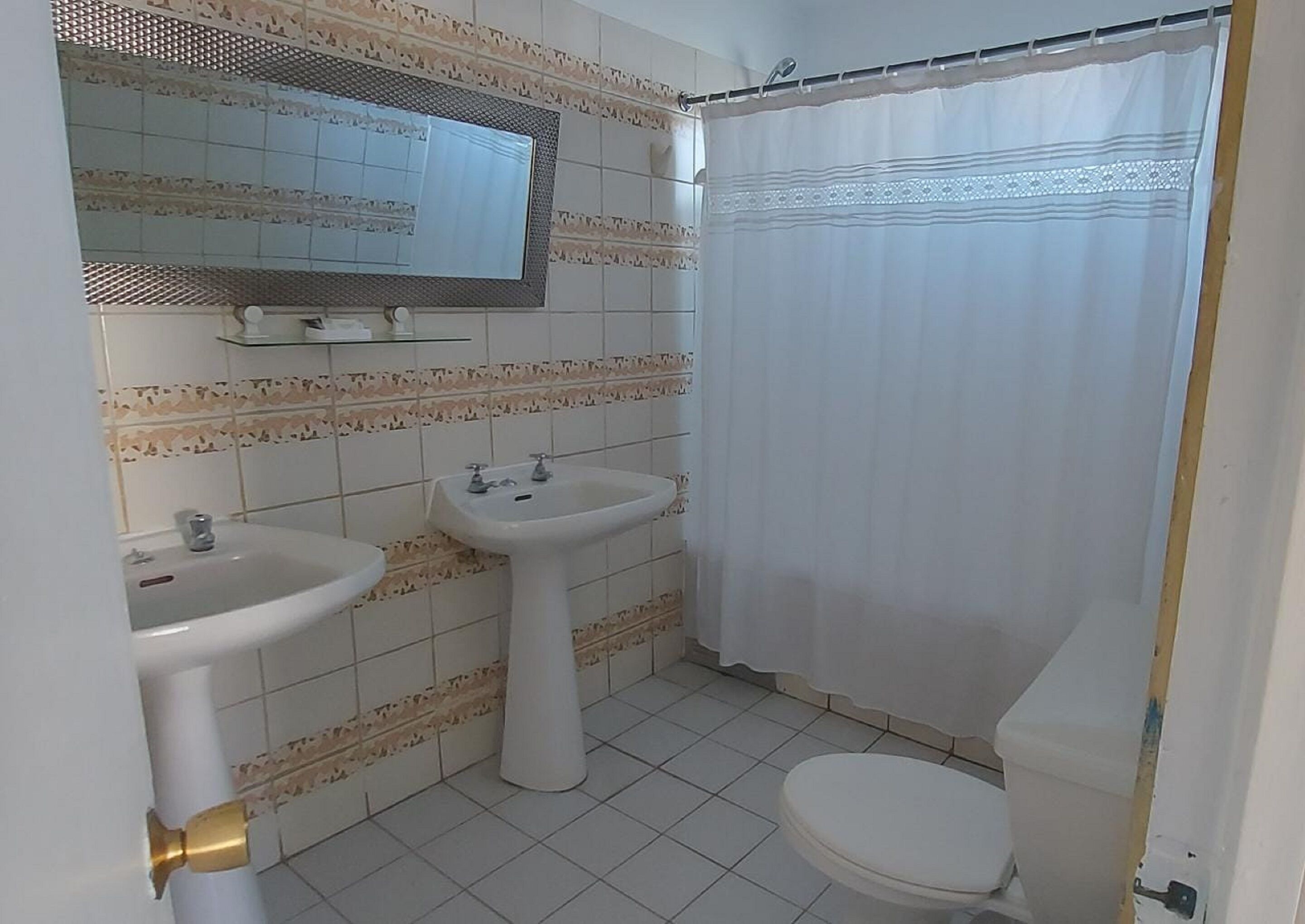 Une salle de bain avec deux lavabos, des toilettes et un rideau de douche.