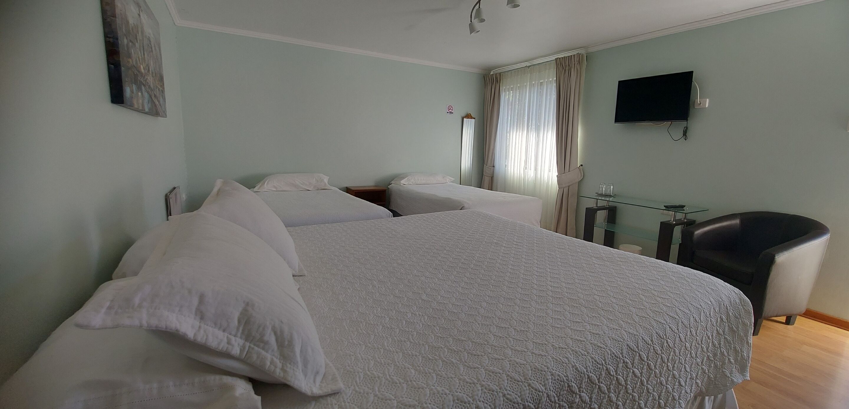 A hotel room with a large bed, a TV mounted on the wall, and a chair.