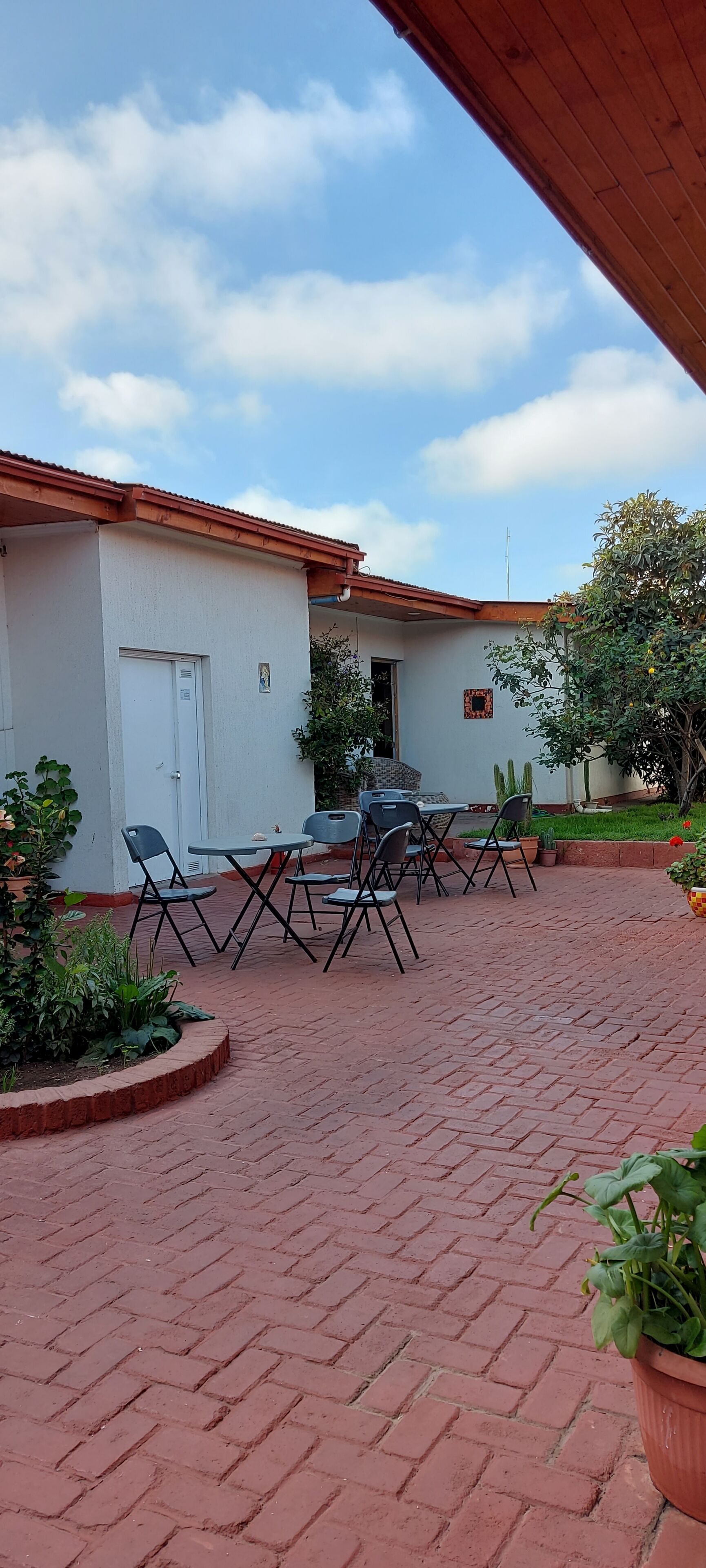 A courtyard with a brick floor, outdoor seating, and potted plants.