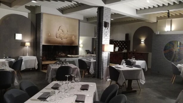 A restaurant with tables set for dining, a fireplace, and a modern interior design. - Le Malatras (Tullins)