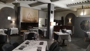 A restaurant with tables set for dining, a fireplace, and a modern interior design. - Le Malatras (Tullins)