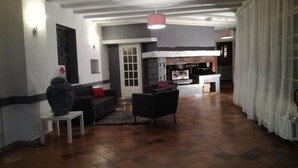 A spacious living area with a fireplace, a sofa, a coffee table, and a dining table. - Le Malatras (Tullins)