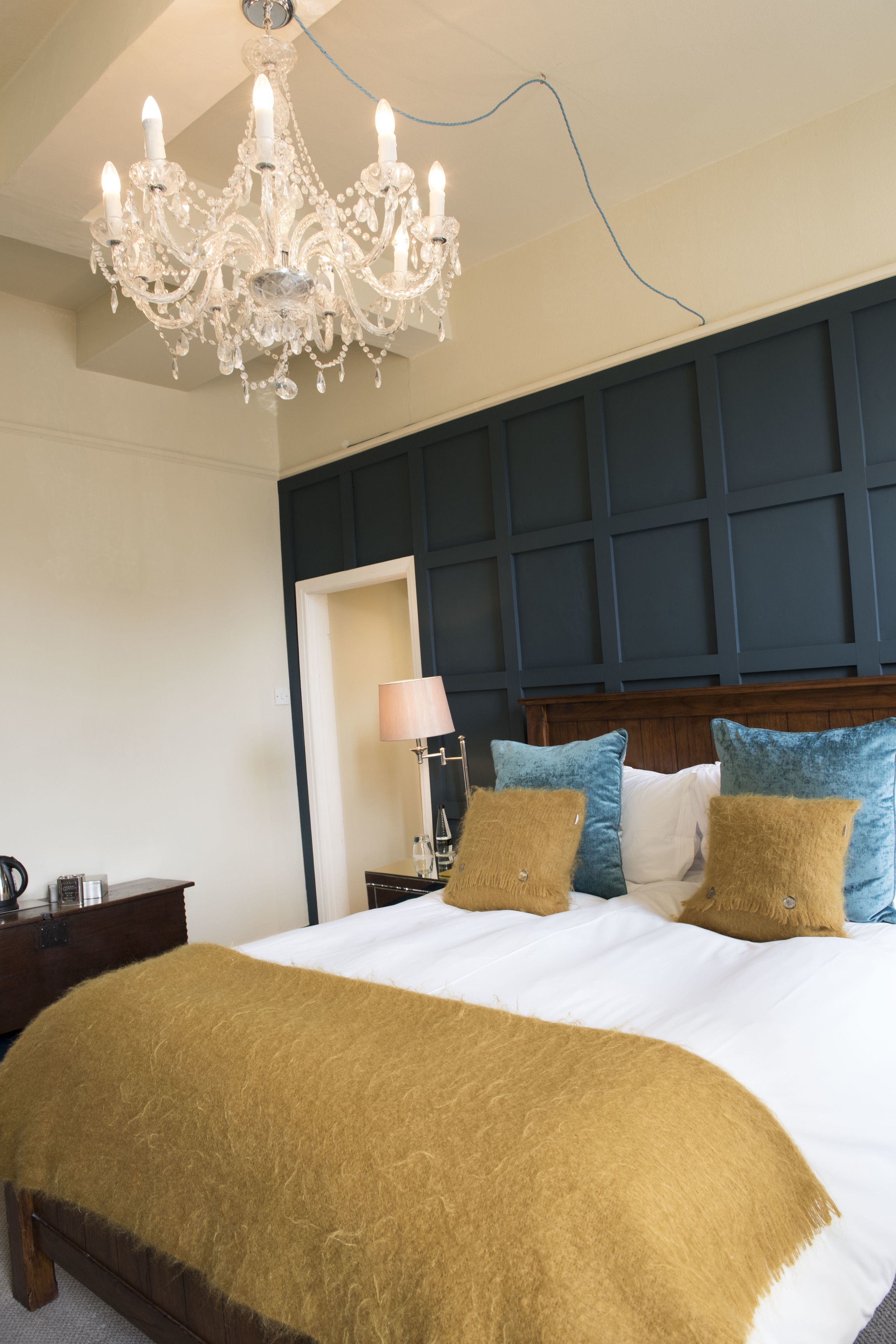 Une chambre à coucher avec un grand lit, un lustre et une tête de lit en bois.