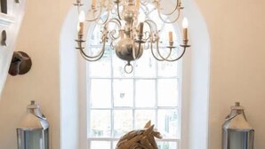 A chandelier, a horse sculpture, and a window with a view in a room with a staircase. - The Priory (Leyburn)