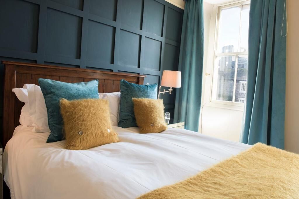 A hotel room with a large bed, a wooden headboard, and a window with curtains.