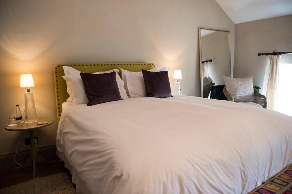 A neatly made bed with white and brown pillows, a green upholstered headboard, and two bedside lamps.