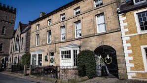 A historic building with multiple windows, a gated entrance, and a small garden area. - The Priory (Leyburn)