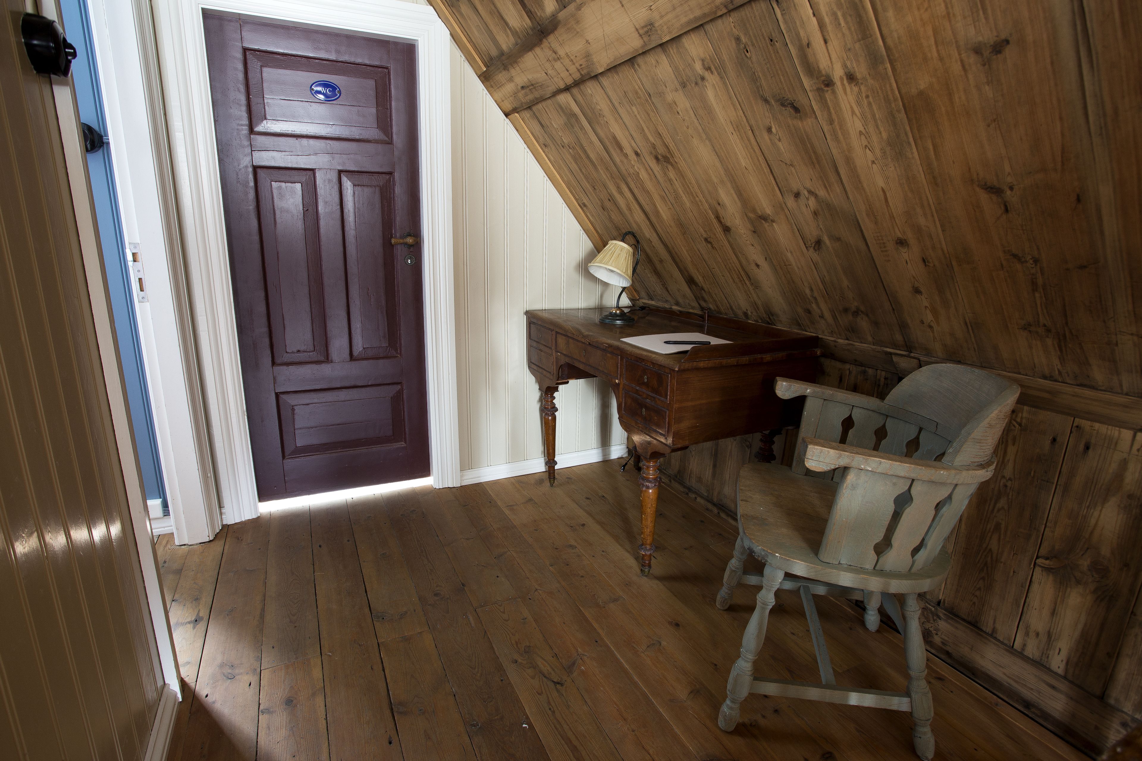 Une pièce avec un plancher en bois, un bureau avec une lampe et une chaise.