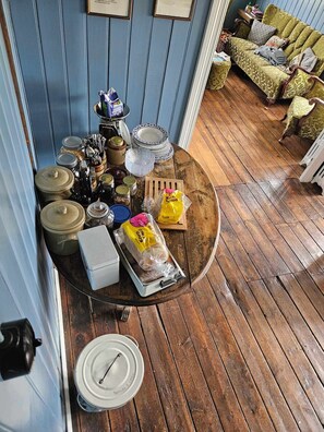 A dining area with a wooden table set with various dishes, utensils, and a bread loaf.
