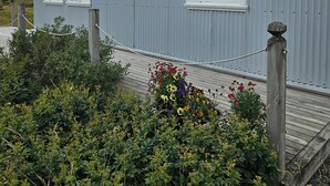 Ein zweistöckiges Gebäude mit einer Wellmetallfassade und einer Holzterrasse.
