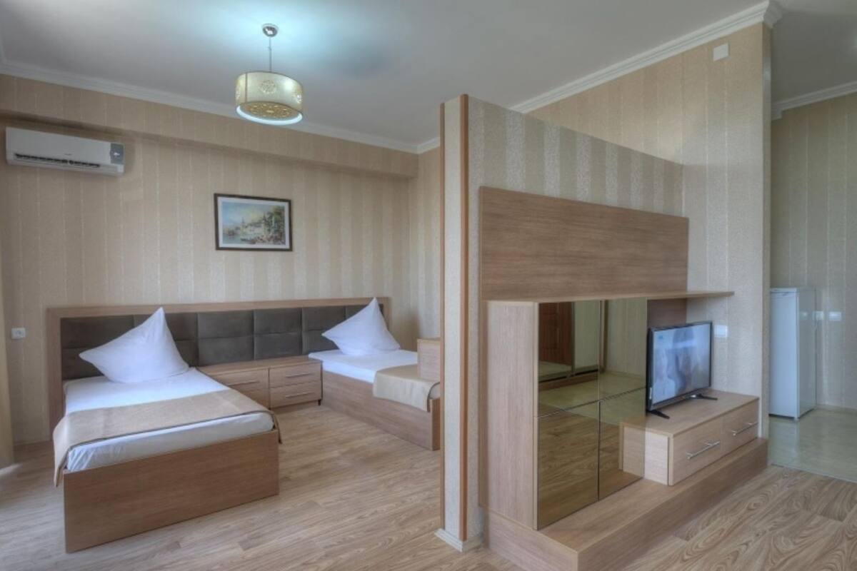 Une chambre moderne avec un grand lit, une télévision et un petit espace bureau.