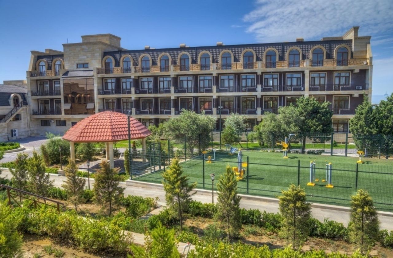 Hotel de diverses plantes amb un pati que inclou un parc infantil i un porxo.