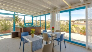 A rooftop restaurant with outdoor seating, large windows, and potted plants. - Hotel Ristorante Trinacria (San Vito Lo Capo)