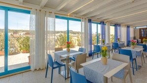 A restaurant with outdoor seating, blue chairs, and tables with flower centerpieces. - Hotel Ristorante Trinacria (San Vito Lo Capo)