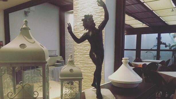 A dining area with a view of the water, featuring decorative lanterns and a statue. - Hotel Ristorante Trinacria (San Vito Lo Capo)