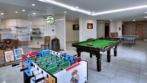 Una habitación con mesa de fútbol de mesa, mesa de billar y mesa de carambola.