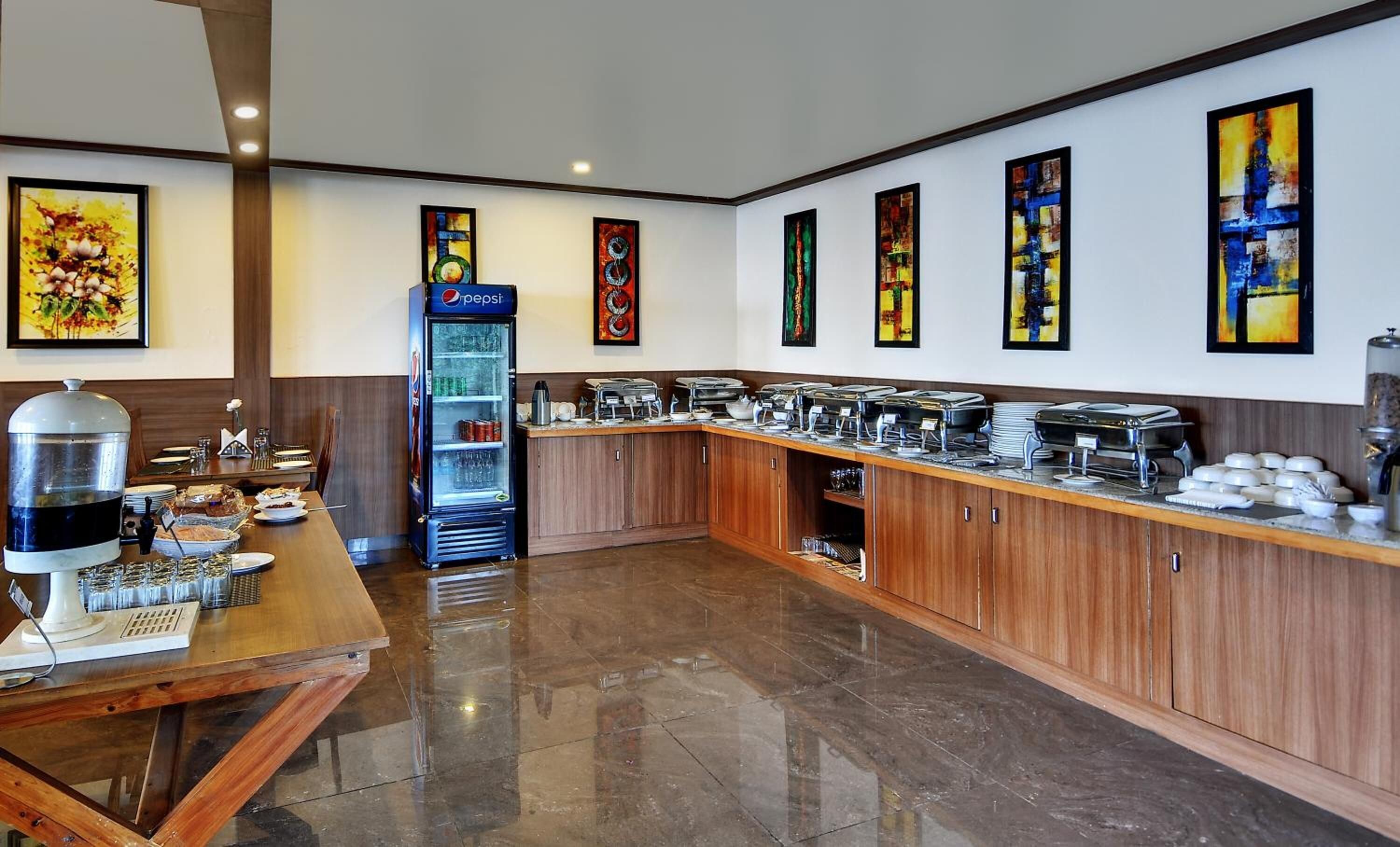A modern kitchen area with a buffet setup, a Pepsi refrigerator, and various food service equipment.