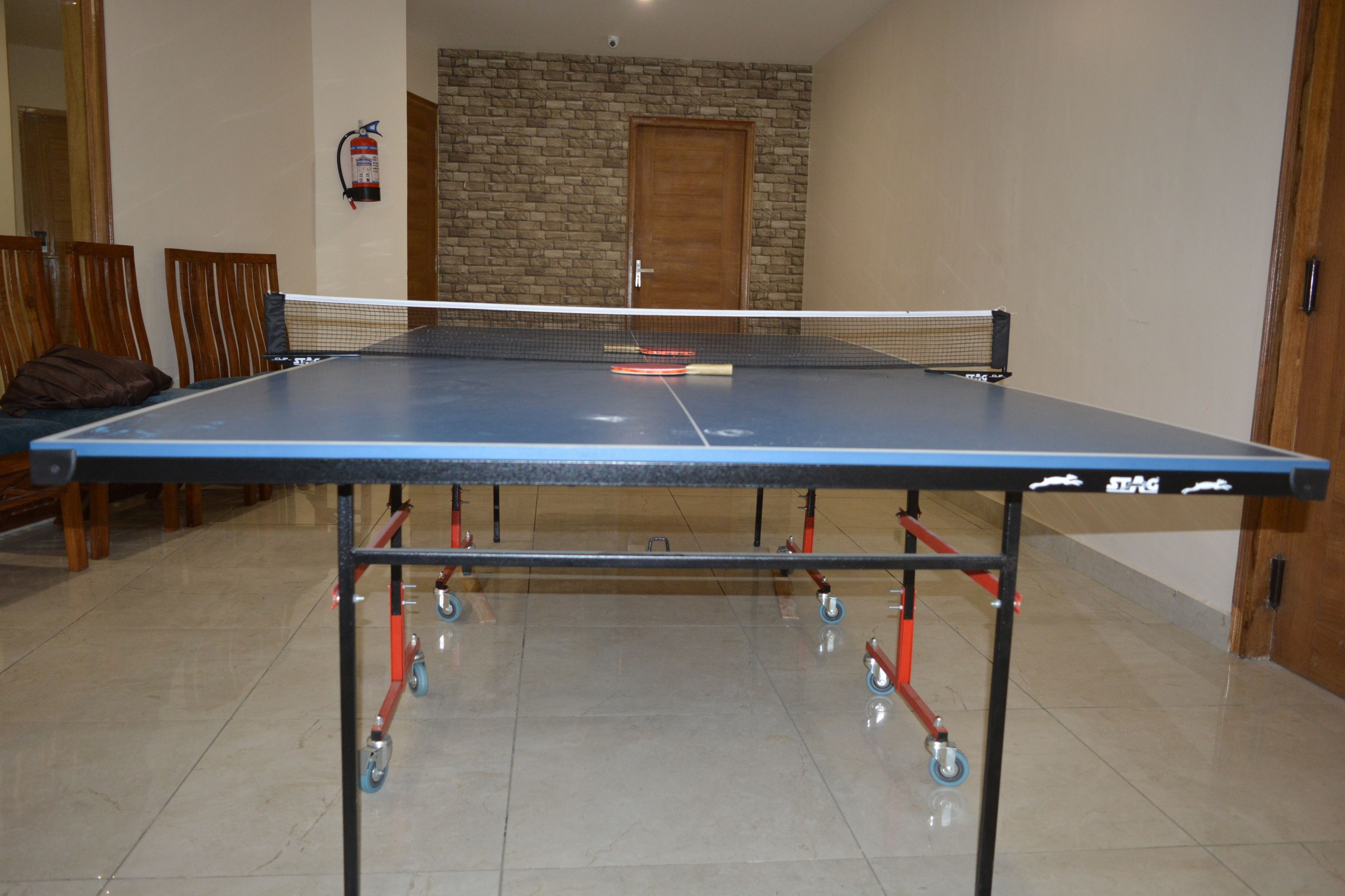 A ping pong table with a net in a room with a stone wall and a wooden door.