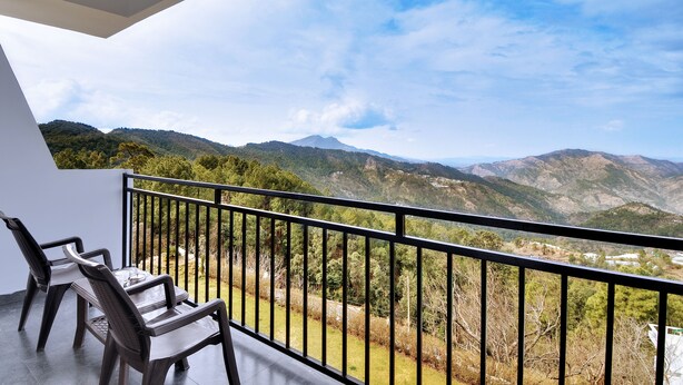 Un balcón con vistas a montañas y una mesa con sillas.