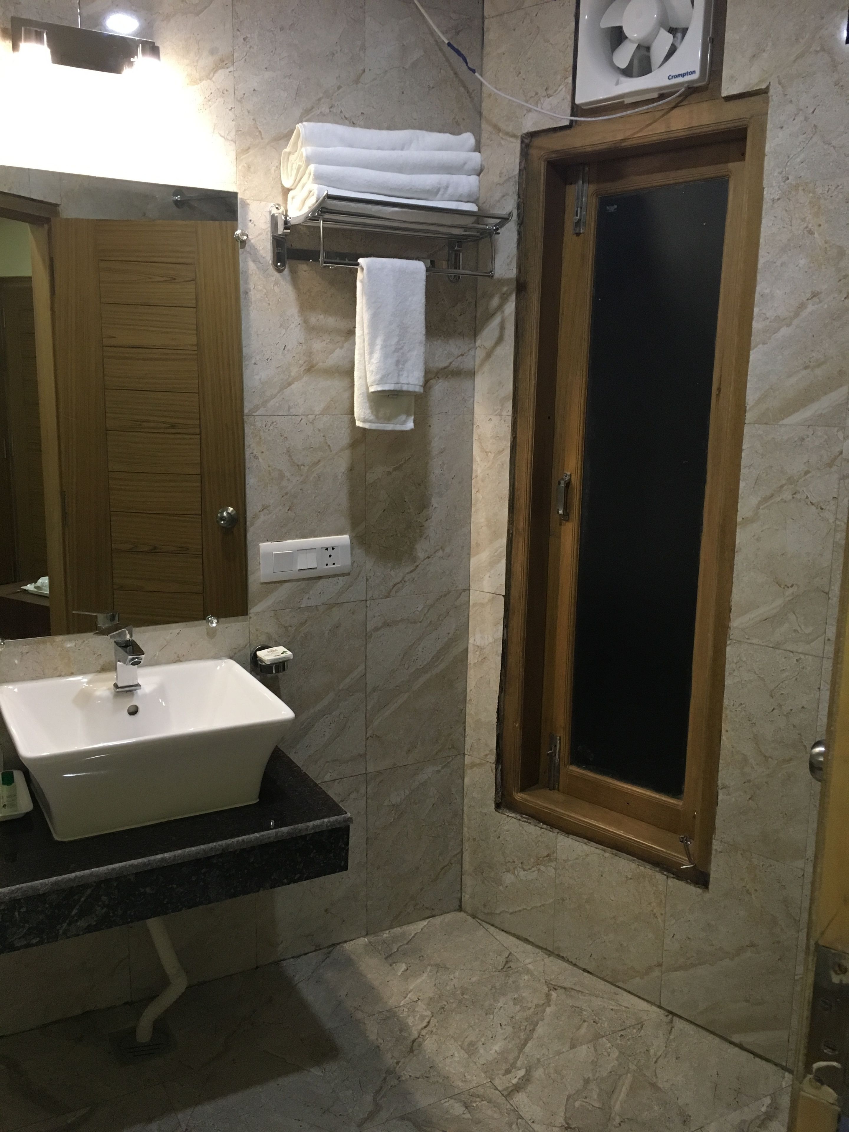 Un baño con lavabo, espejo, toallero y puerta.