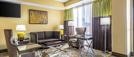 Une chambre d’hôtel avec un canapé, un fauteuil et une petite table avec des lampes.