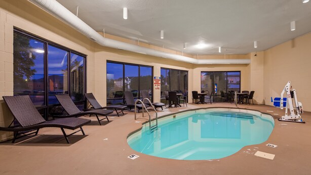 An indoor pool area with lounge chairs, tables, and a lifeguard stand. - Quality Inn & Suites Southport (Indianapolis)