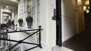 Ein Hotelgang mit schwarzer Metallreling, Blumentöpfen und einem Schild an der Wand.