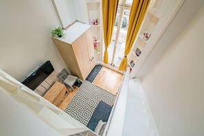 A compact room with a bed, a small desk, a plant, and a window with curtains. - Clarincarde Gardens Apartment (London)