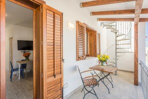 A balcony with wooden shutters, a table with chairs, and a spiral staircase. - Case Vacanze Trinacria (San Vito Lo Capo)