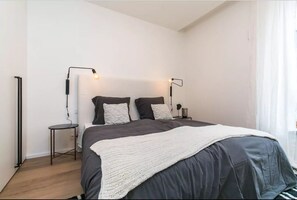 A modern bedroom with a large bed, two bedside tables, and two floor lamps. - Flawless Apartments Pod Děkankou (Prague)