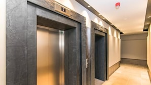A hallway with three elevator doors, each marked with a number. - Flawless Apartments Pod Děkankou (Prague)